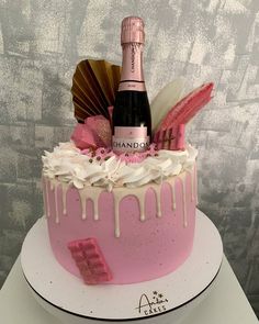 a cake decorated with pink icing, white frosting and a bottle of champagne