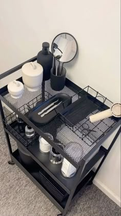 a black metal cart with two trays and utensils on the bottom shelf