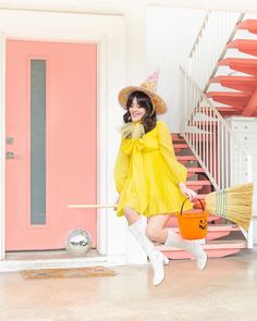 a woman in a yellow dress holding a broom and bucket