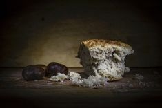 a piece of bread sitting on top of a wooden table next to an acorn