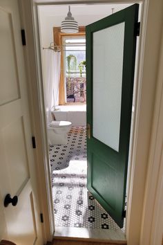 an open door leading to a bathroom with a toilet and tub in the background on a tiled floor