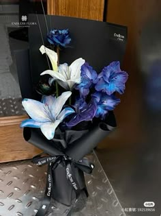 blue and white flowers are wrapped in black paper