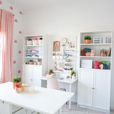 a white desk and chair in a room with pink curtains on the window sill