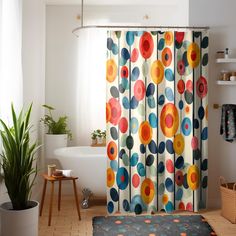 a colorful shower curtain in a bathroom with potted plants on the floor and a bathtub