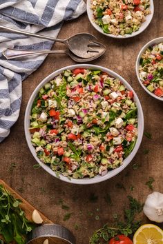 two bowls filled with salad on top of a table next to sliced lemons and garlic