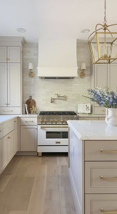 a kitchen with white cabinets and an island in the middle is lit by two pendant lights