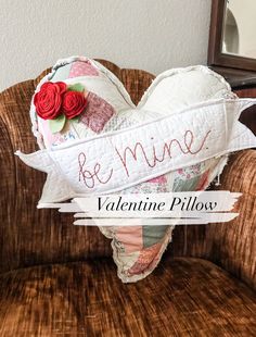 a heart shaped pillow sitting on top of a chair with the words be mine written on it