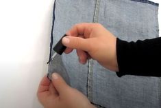 someone is cutting up the edge of a piece of denim fabric with a pair of scissors