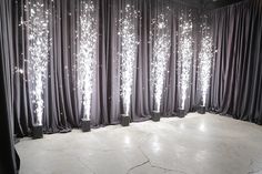 an empty room with black drapes and white flowers on the curtained wall behind it