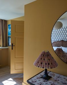 a bedroom with yellow walls and a mirror on the wall, next to a bed