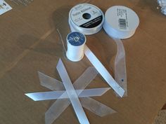 two rolls of white ribbon sitting on top of a cardboard box next to some scissors