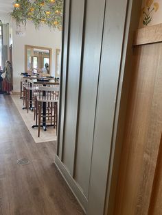 an open door leading to a dining room with wooden tables and bar stools in it