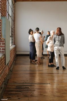 a group of people are standing in an empty room looking at something on the wall