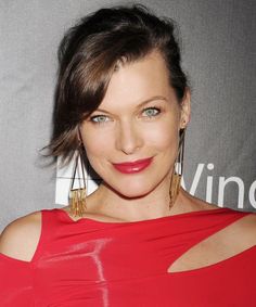 a woman in a red dress posing for the camera with large earrings on her head