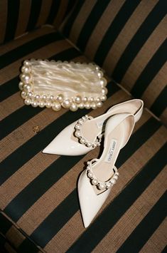 a pair of white shoes sitting on top of a striped couch next to a purse