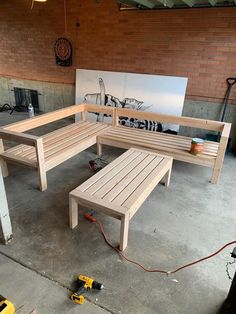 two wooden benches sitting next to each other on top of a cement floor in front of a brick wall