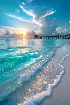 the sun is setting over an ocean with waves coming in to shore and a pier stretching out into the distance