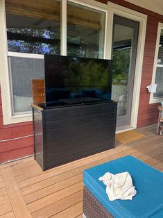 a flat screen tv sitting on top of a wooden floor next to a blue ottoman