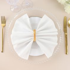 a place setting with white napkins and gold cutlery