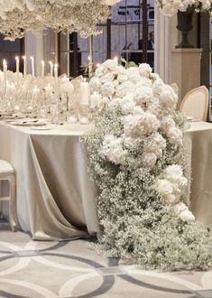 the table is set with white flowers and candles for an elegant wedding reception or special event