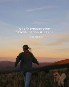 a woman walking down a hill with her dog in the foreground and an image of mountains in the background