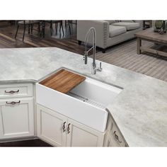 a white kitchen sink sitting under a faucet next to a wooden cutting board