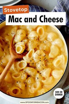 a bowl filled with macaroni and cheese on top of a counter next to a wooden spoon