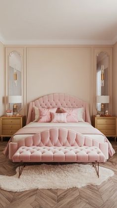 a bed with pink velvet upholstered headboard and footstools in a bedroom