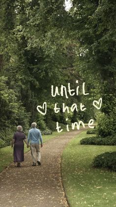 an older couple walking down a path in the park together, holding hands and looking at each other