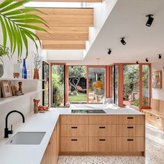 a kitchen with wooden cabinets and white counter tops next to a large window that looks out onto the backyard