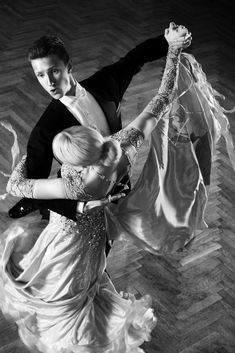 a man and woman are dancing together on the dancefloored floor in black and white