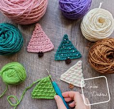 crochet christmas tree ornaments are displayed on a table with yarn balls and scissors