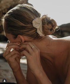 a woman is sitting on the beach with her hands to her face