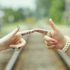 two women holding out their fingers with the words best friends written on them