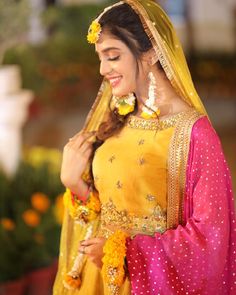 a woman wearing a yellow and pink outfit with flowers in her hair is smiling at the camera