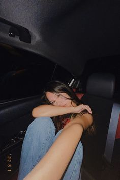 a woman sitting in the back seat of a car with her arm resting on her head