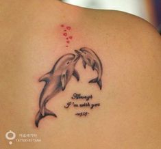 two dolphins on the back of a woman's shoulder with words written below them