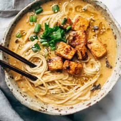 a bowl filled with noodles, tofu and green onions