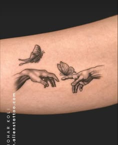 two hands touching each other with a butterfly flying above them on the right side of the arm