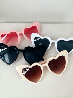 several heart shaped sunglasses are sitting on a counter top, one is white and the other is pink