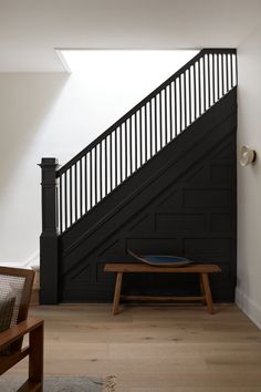 a wooden bench sitting under a stair case