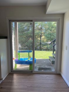 an empty room with sliding glass doors leading to a play area in the back yard