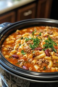 a crock pot filled with pasta and ground beef in a tomato based broth