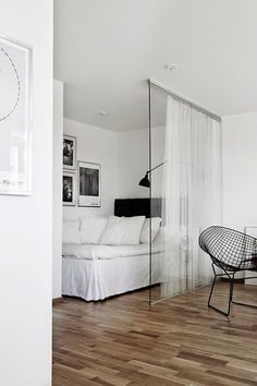 a living room with wood floors and white walls, including a large glass door to the bedroom