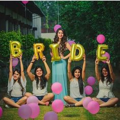 a group of women sitting on the ground holding up balloons in front of their faces