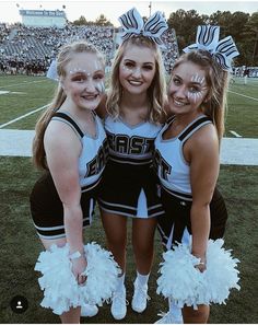 three cheerleaders pose for a photo on the field