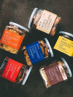 six different types of baked goods in glass containers on the ground with labels for them