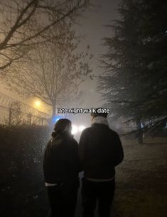 two people standing in the rain at night