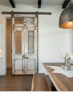 an old door is opened to reveal a dining room with wooden table and bench in the foreground