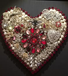 a heart shaped brooch with pearls and jewels